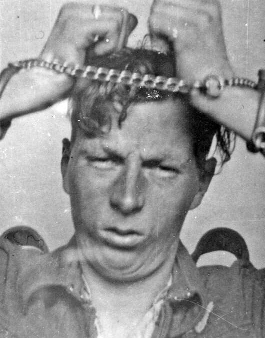 A male prisoner of war with his wrists chained together.